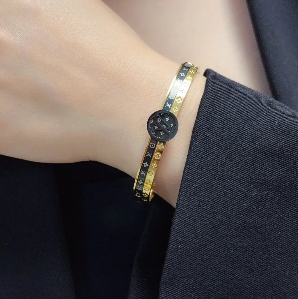 Gold and black designer bangle bracelet on wrist