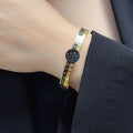 Gold and black designer bangle bracelet on wrist
