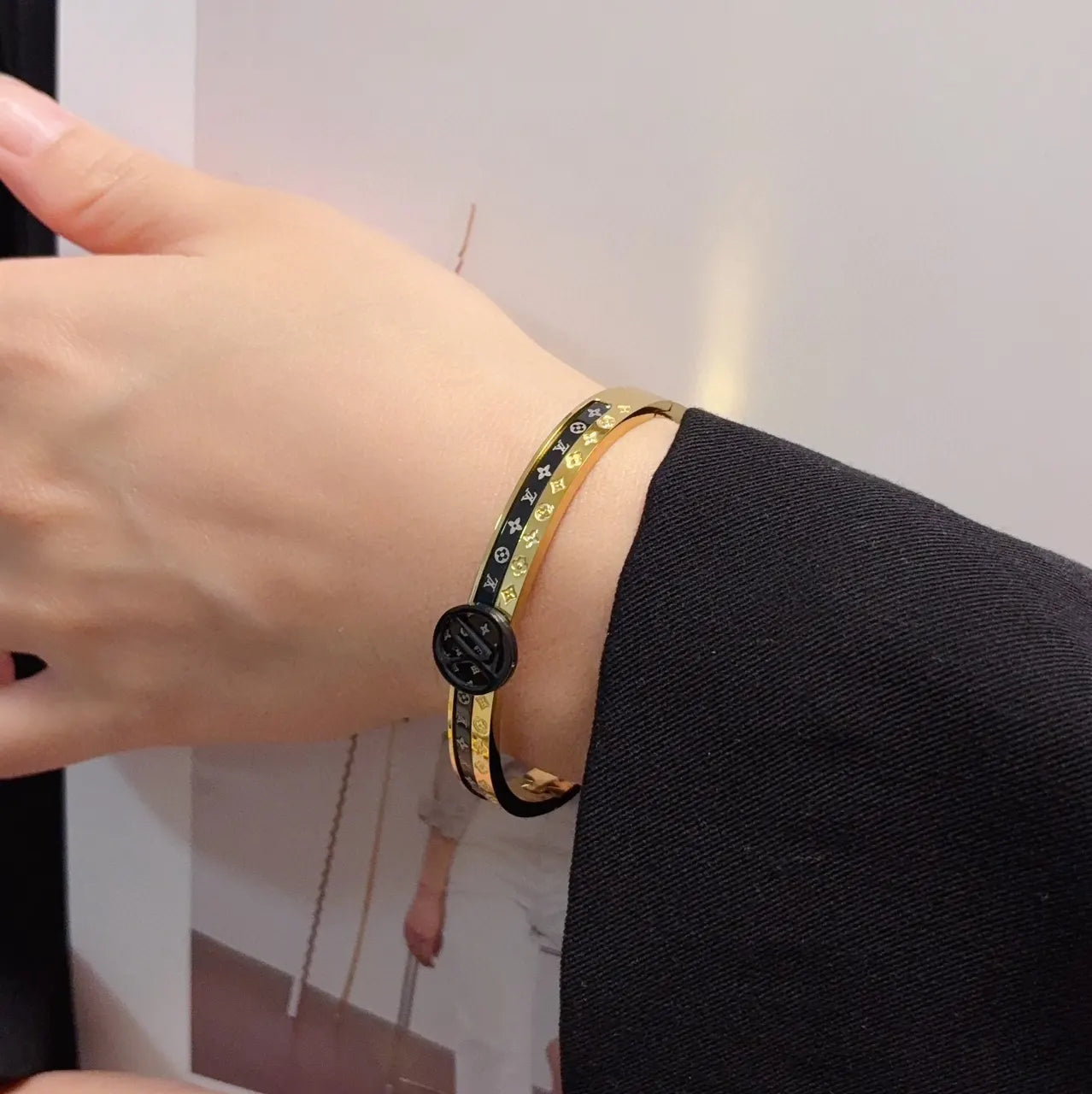Gold and black designer bangle bracelet on wrist - Hình 2
